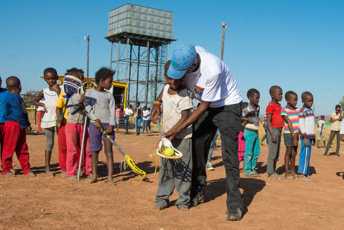 A coach teaching a child how to hold a lacrosse stick for the first time in Vaalwater