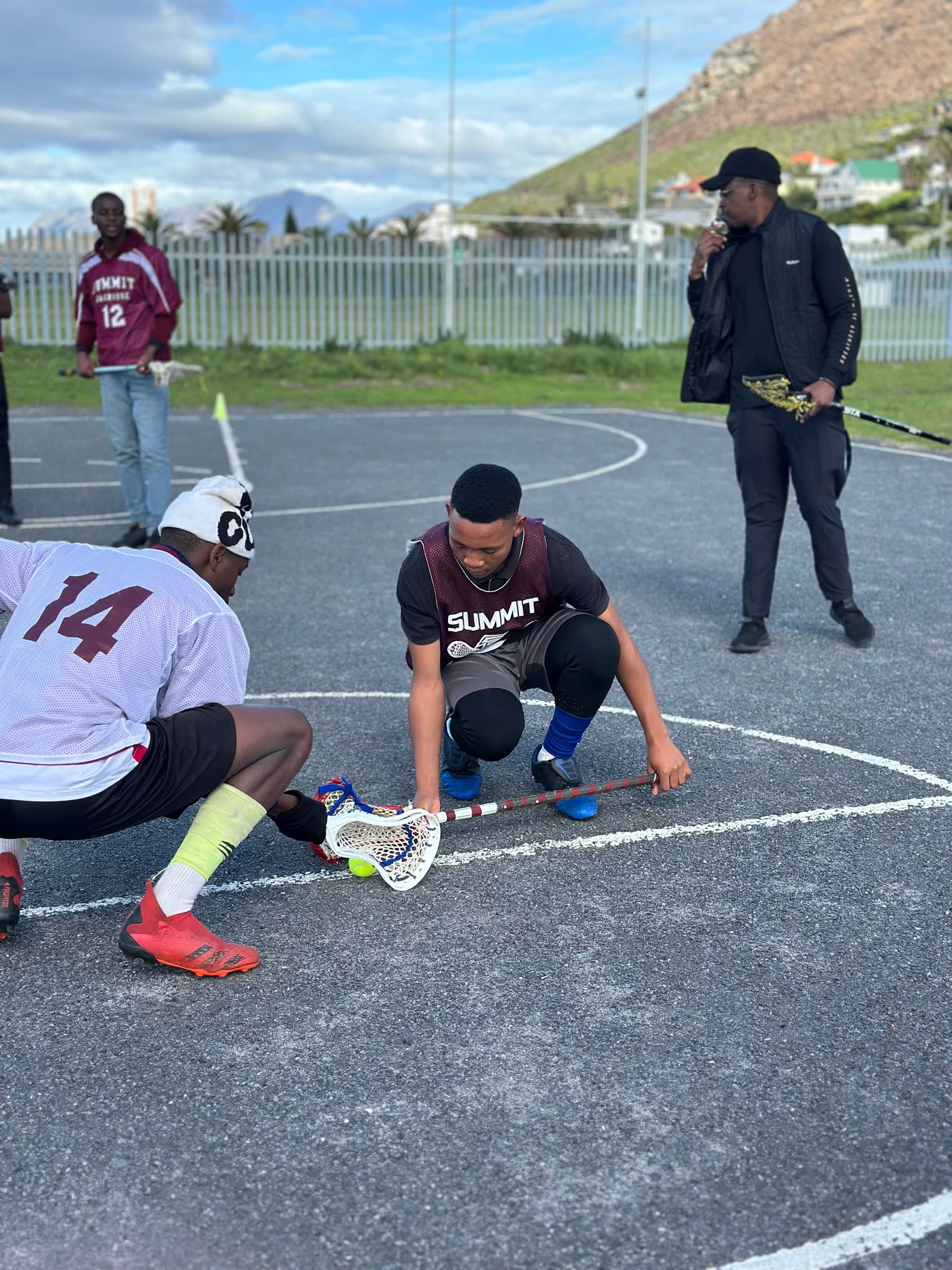 Players and a coach in a circle before a draw in Muizenberg