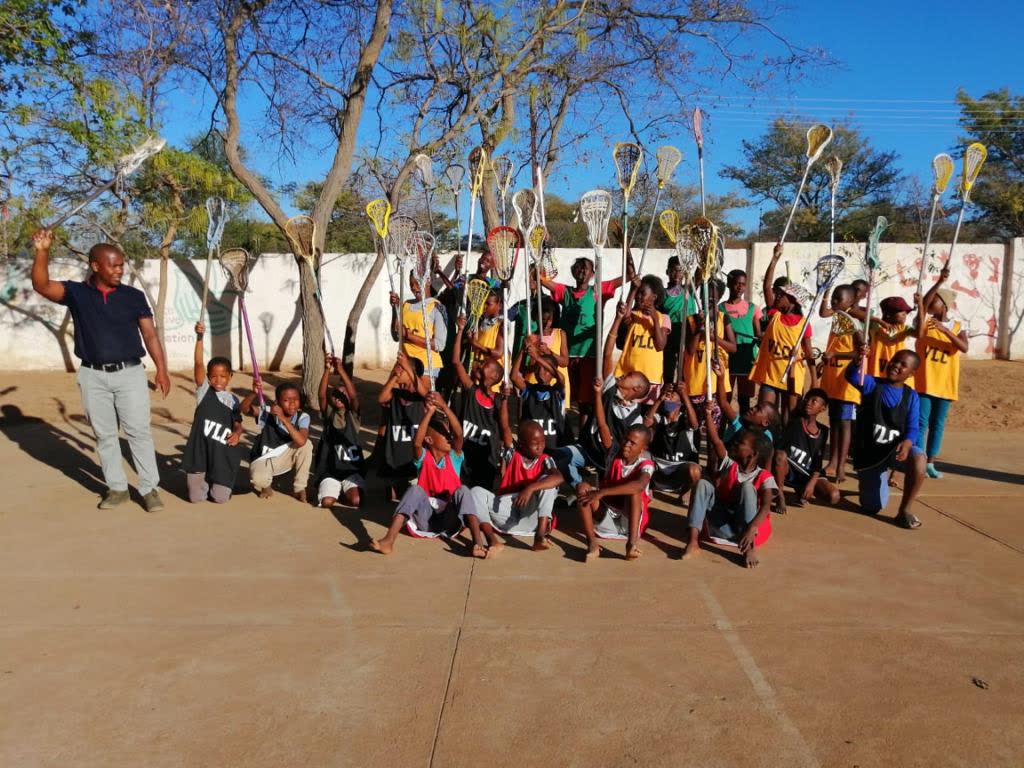 The Vaalwater Lacrosse Club team and coach with sticks raised
